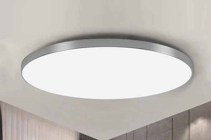 Round ceiling panel light fixture with a white diffuser mounted flush to the ceiling in a modern room.